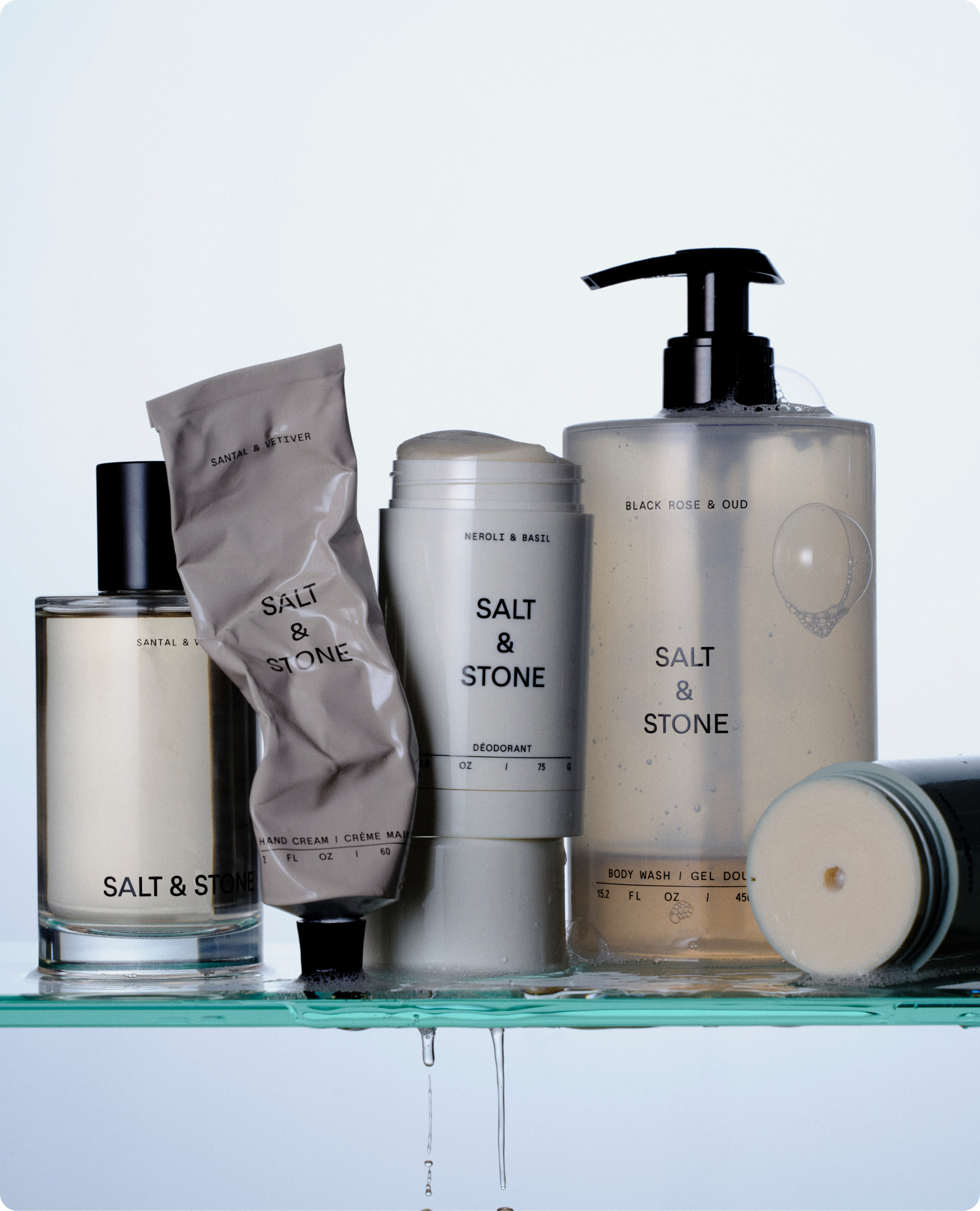 Salt & Stone fragrance, hand cream, deodorant and body wash arranged on a glass shelf